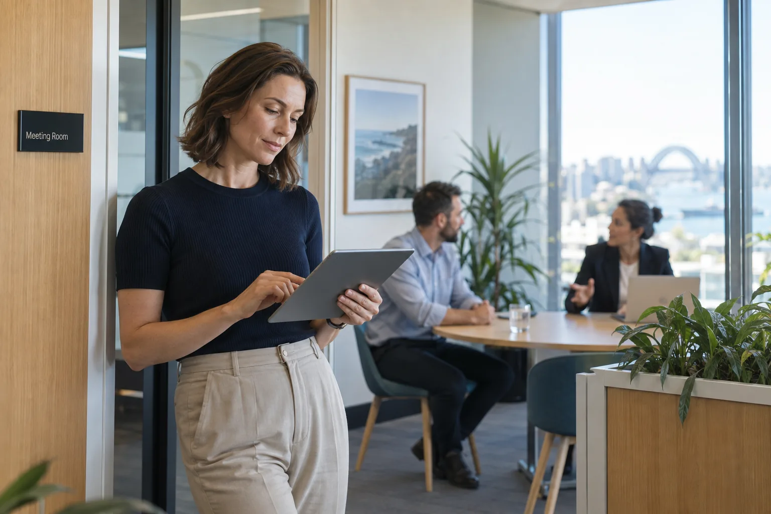 Illustrative office scene of a manager reviewing a request on a tablet while colleagues continue their work